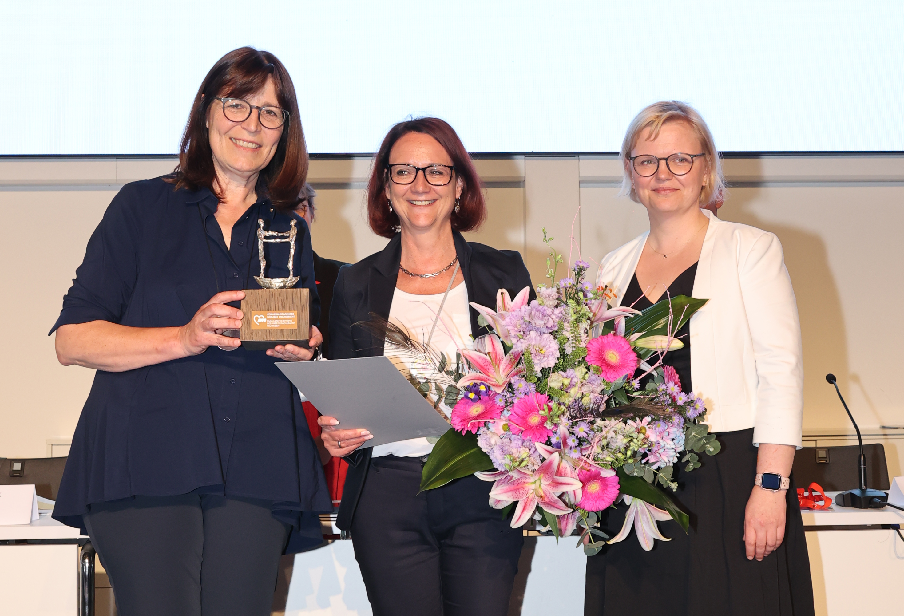 AWO-Landesvorsitzende Petra Rottschalk (links) und AWO-Landesgeschäftsführerin Katja Glybowskaja (rechts) überreichen Claudia Zanker die Emma-Sachse-Ehrung, die höchste Auszeichnung der AWO Thüringen.